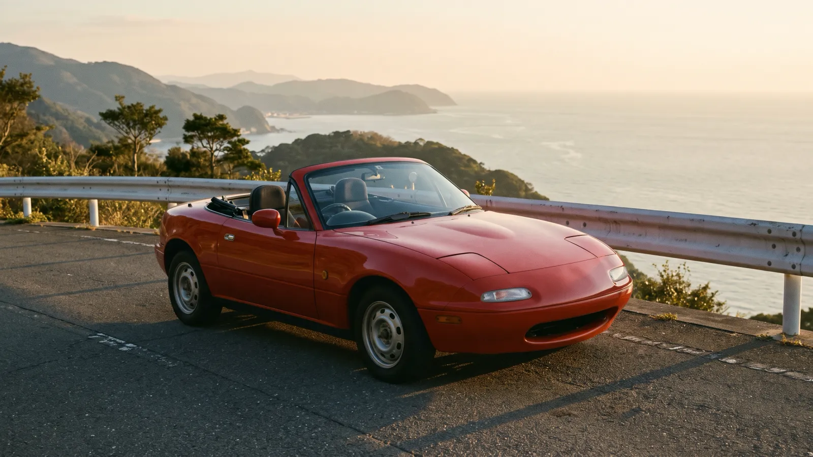 平成元年〜平成5年（1989〜1993年ごろ）のマツダのユーノスロードスターを再現したイメージ。海を見下ろす峠の展望台のガードレールの前に停めた、幌をたたんだ低く小さな赤いオープンカーと、夕方の金色の光。