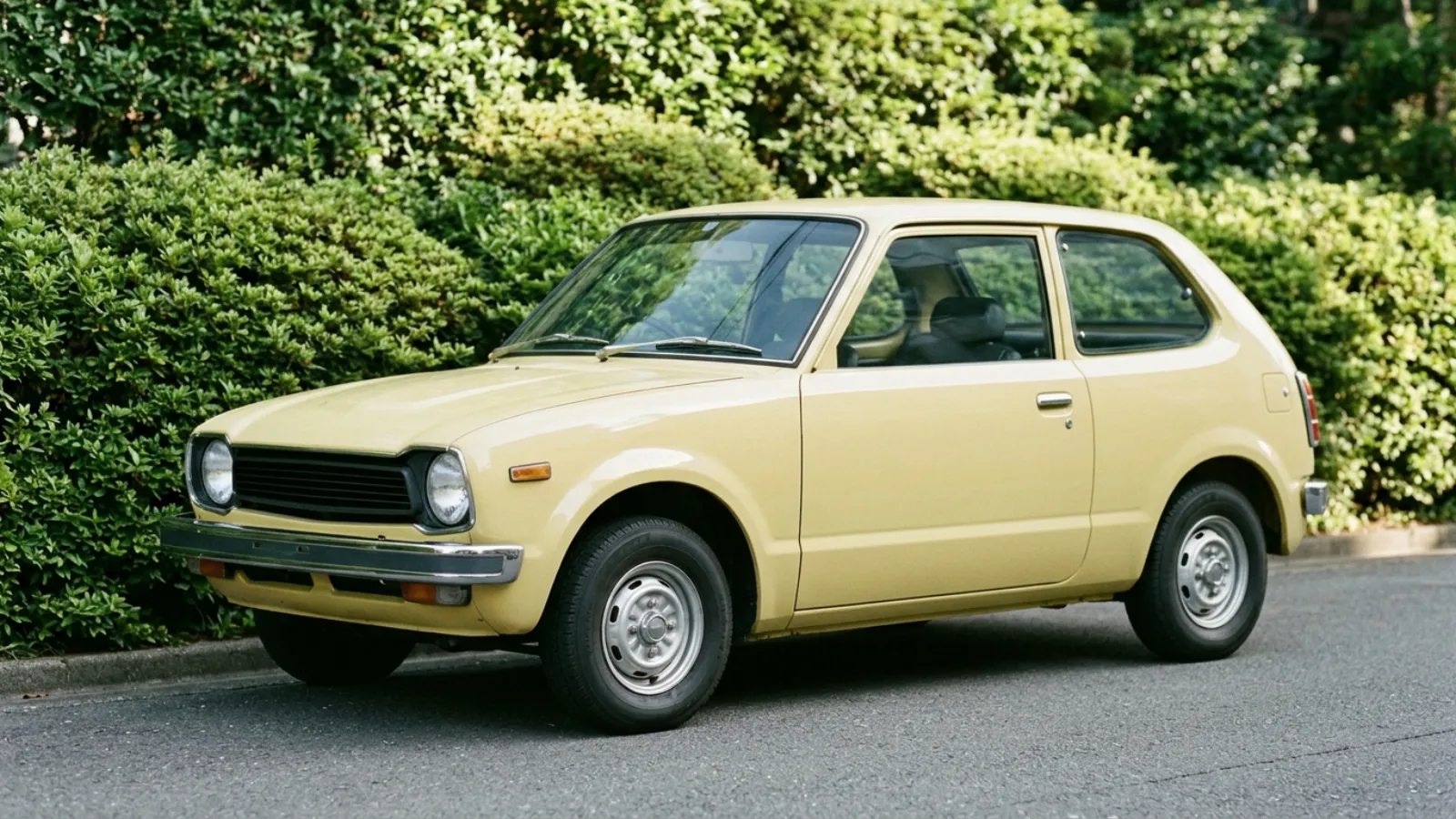 昭和47年〜昭和51年（1972〜1976年ごろ）のホンダのシビックを再現したイメージ。やわらかな春の光の静かな住宅街で、無地の生け垣の前に、短い鼻先と丸いヘッドライト、細いバンパーをもつ淡い黄色の小さな2ドア車が一台だけ停まっている。